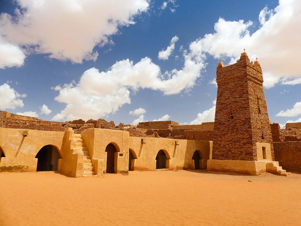 The stone minaret and sand-filled courtyard of the old mosque at Chinguetti in the Mauritanian desert.