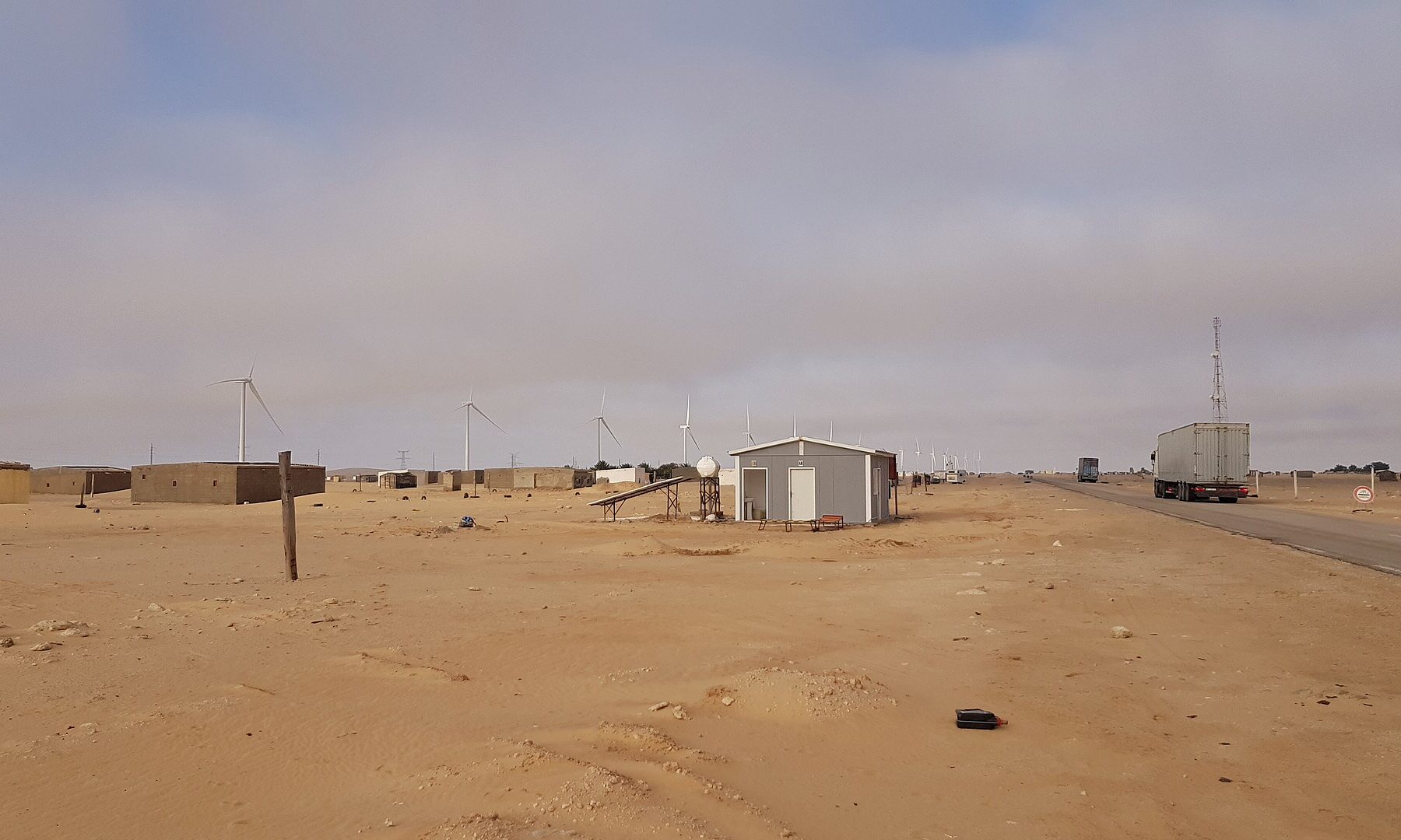 Wind turbines and power pylons beside a roadside settlement on the N2 highway in northern Mauritania