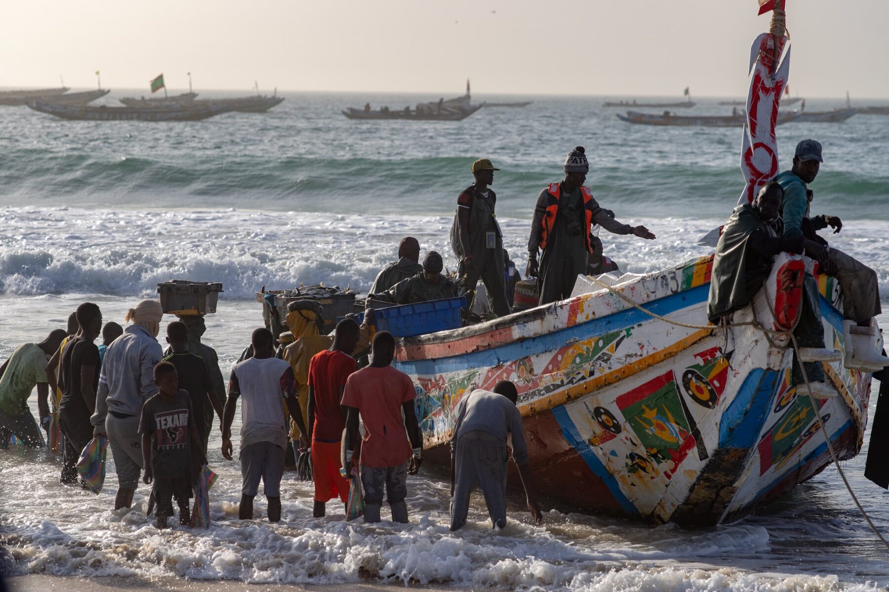 Fishermen unload a painted wooden pirogue on the beach in Nouakchott, Mauritania