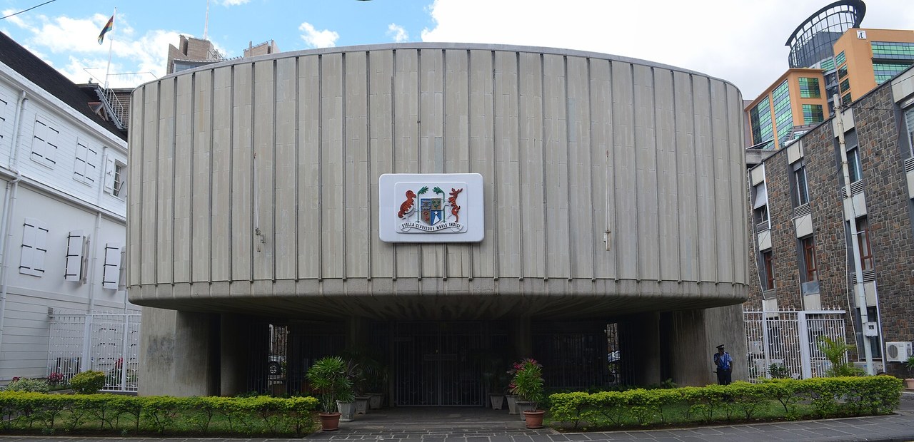 Round concrete facade of the Parliament building in Port Louis, Mauritius, with the national coat of arms on the front