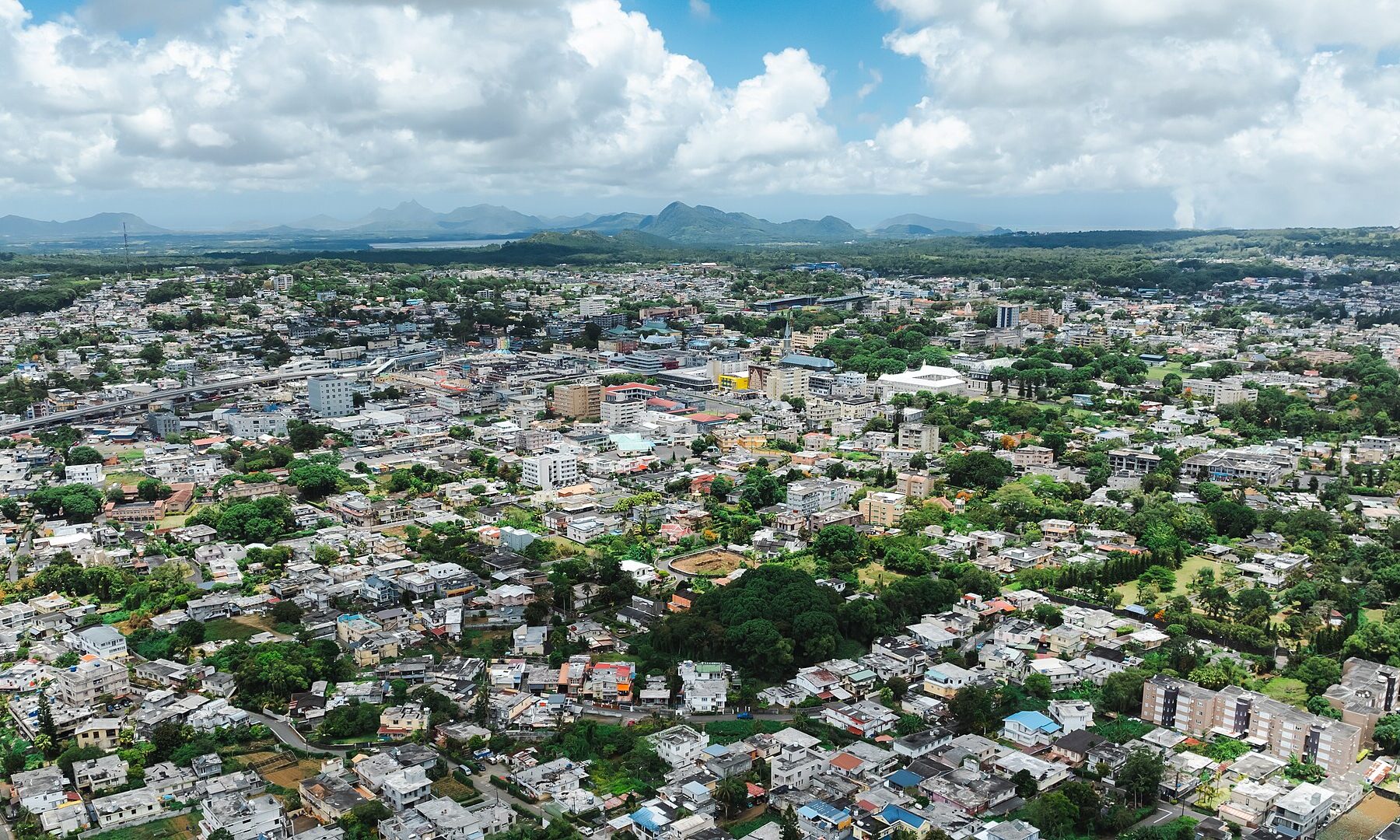 Aerial view of Curepipe, a highland town in central Mauritius, with rooftops, trees and mountains on the horizon