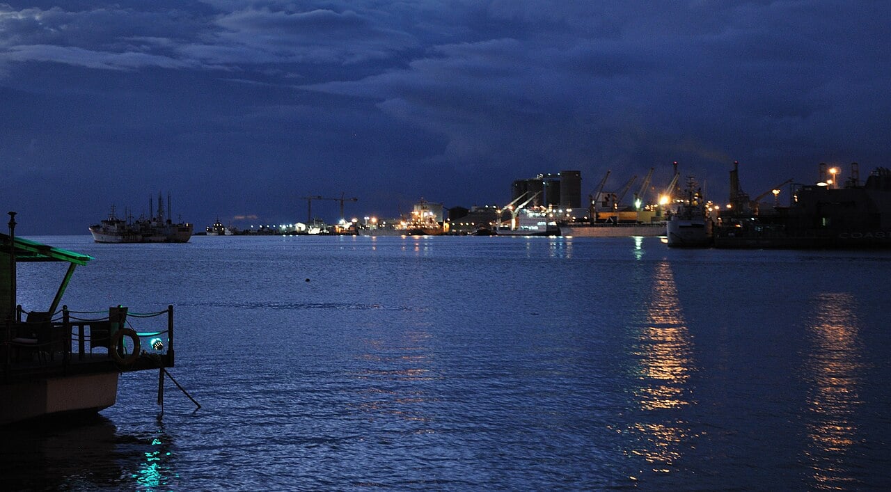 Port Louis harbour at night with ships, cranes and lights reflected on the water
