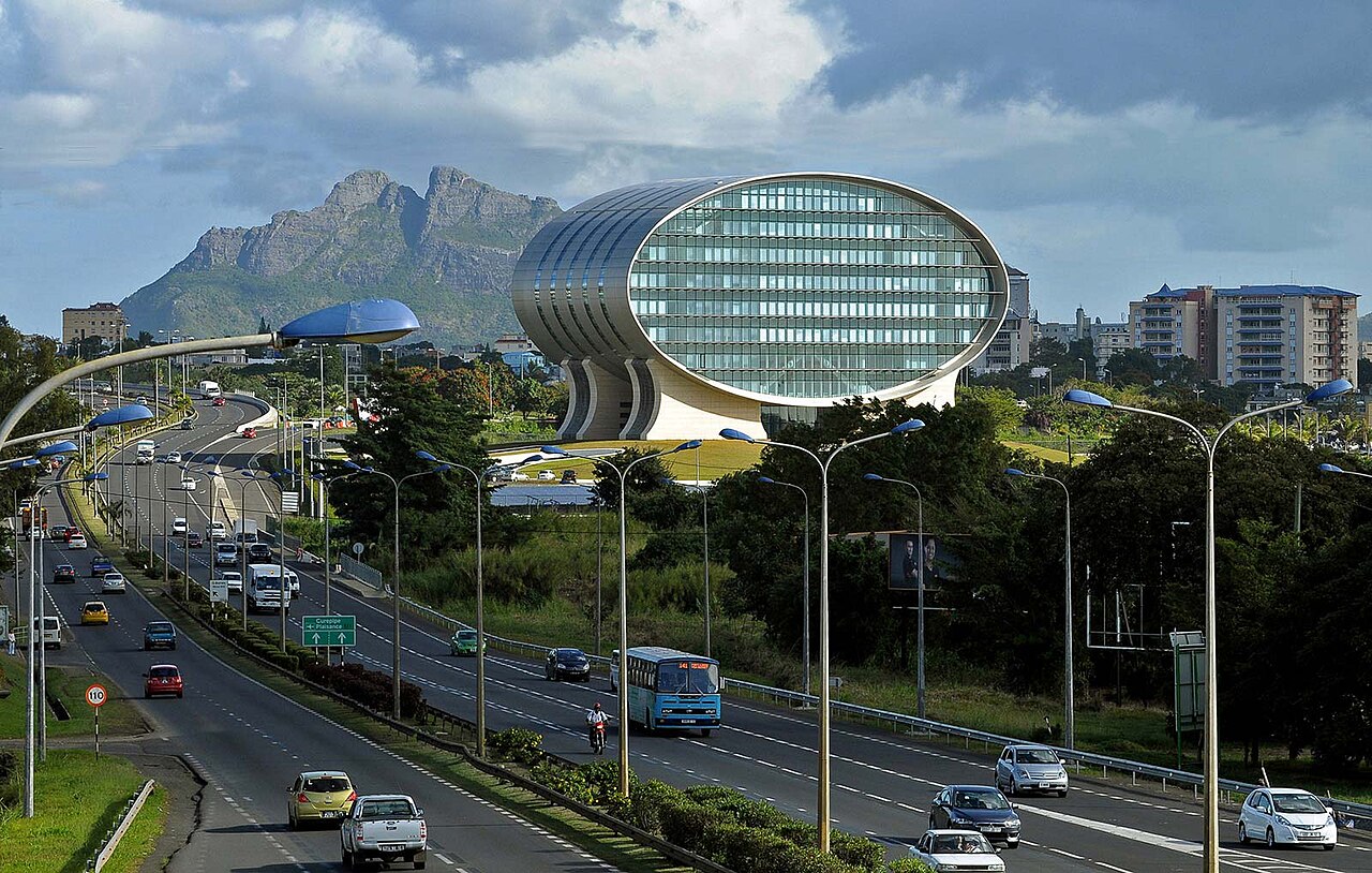 Oval glass office building beside a busy highway with a rocky mountain behind, Ebene Cybercity, Mauritius