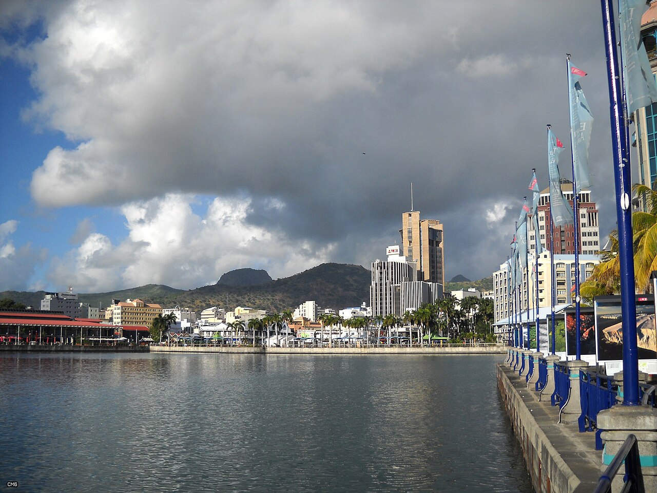 Waterfront of Port Louis, Mauritius, with bank towers, hills and moored boats under heavy cloud