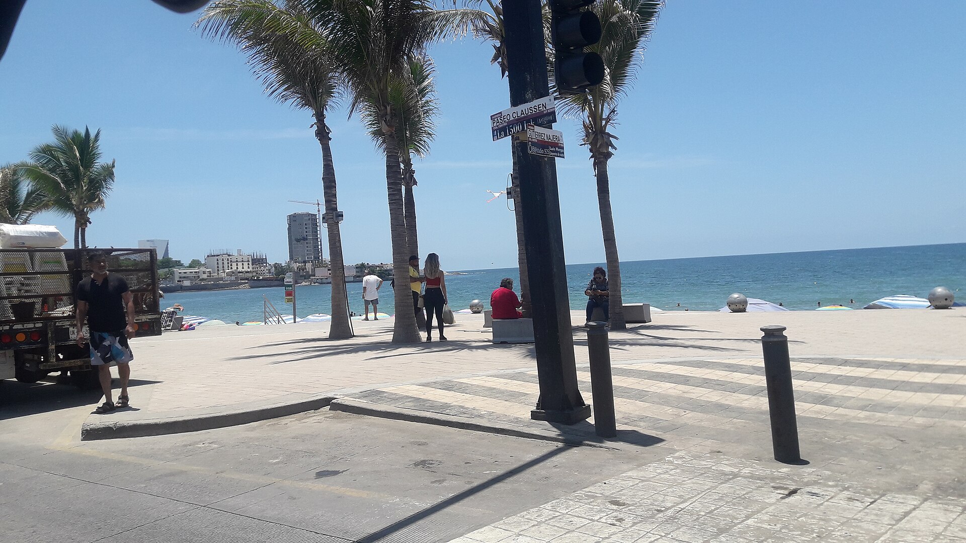 Palm trees and the beach along the Malecón at Paseo Claussen in Mazatlán, Mexico, on a sunny day