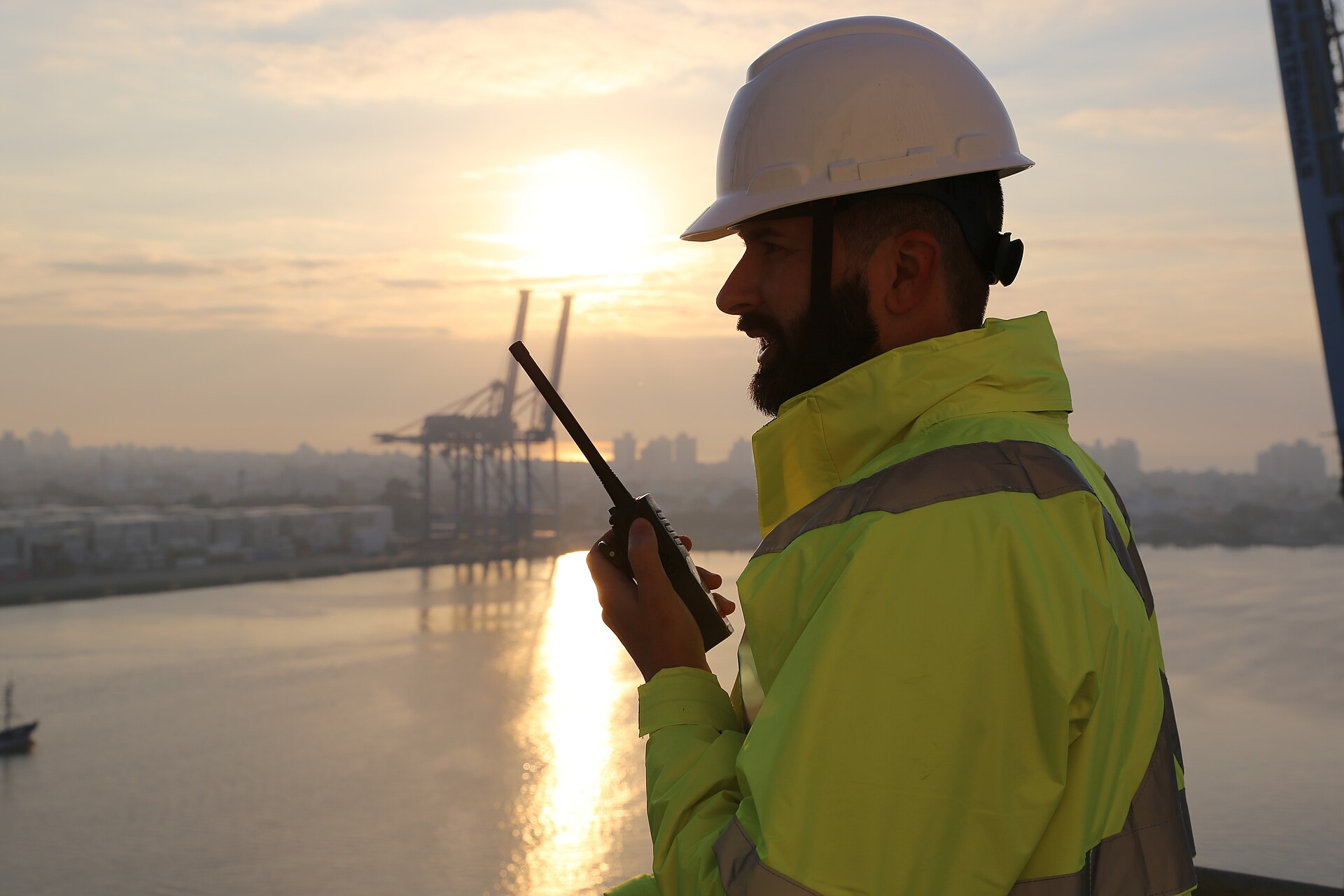Port worker pointing across the harbour at sunrise with container cranes at the Port of Itajaí, Santa Catarina, Brazil
