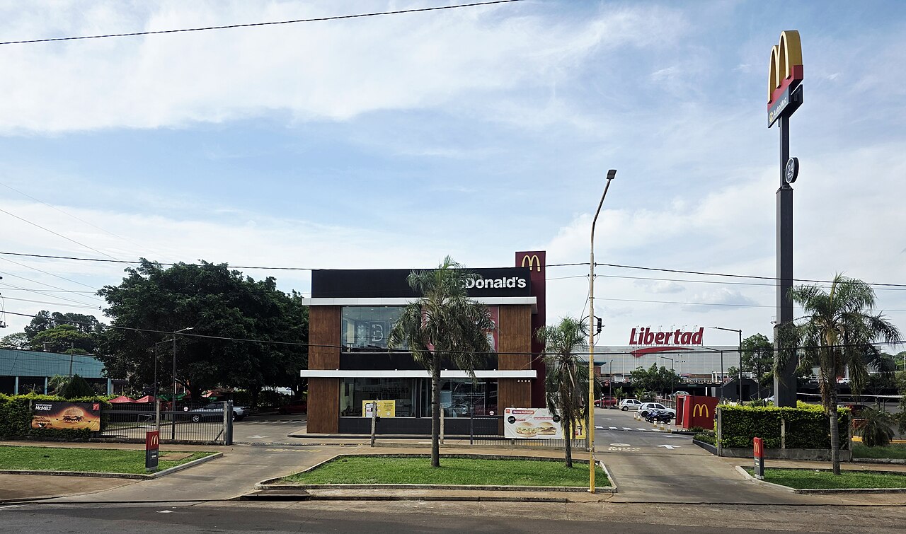 A freestanding McDonald's restaurant with a tall golden arches sign beside a street in Posadas, Argentina