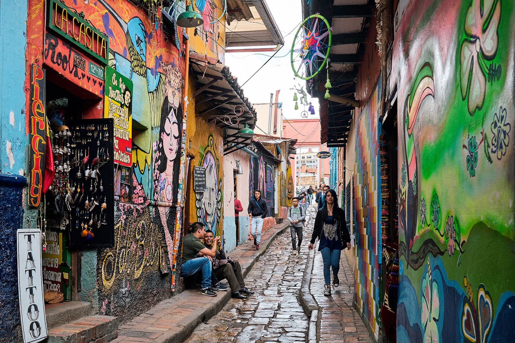 A mural-covered cobblestone lane in La Candelaria, the historic centre of Bogotá, Colombia