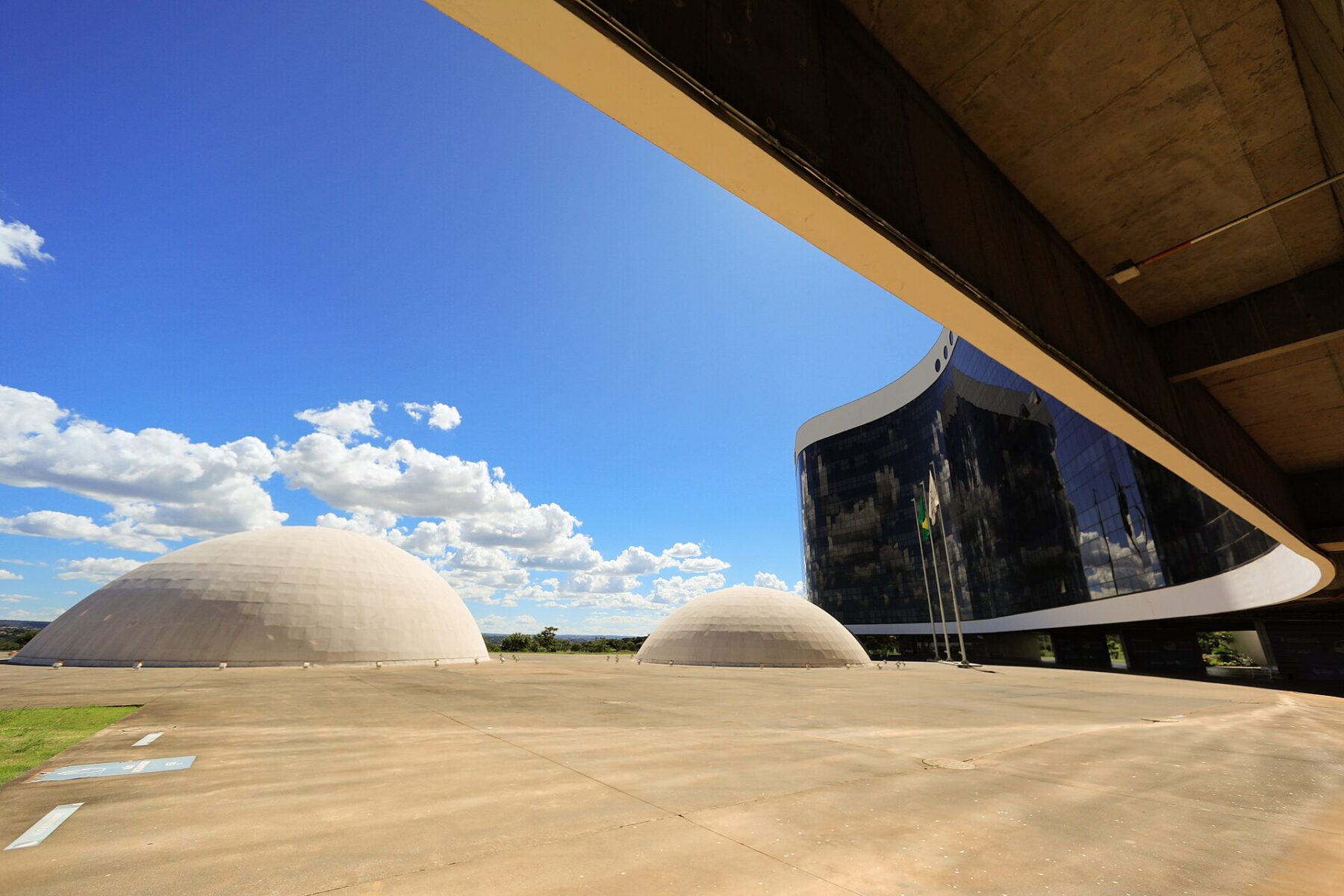 Two white domes and the glass-fronted Superior Electoral Court building under a blue sky in Brasilia, Brazil