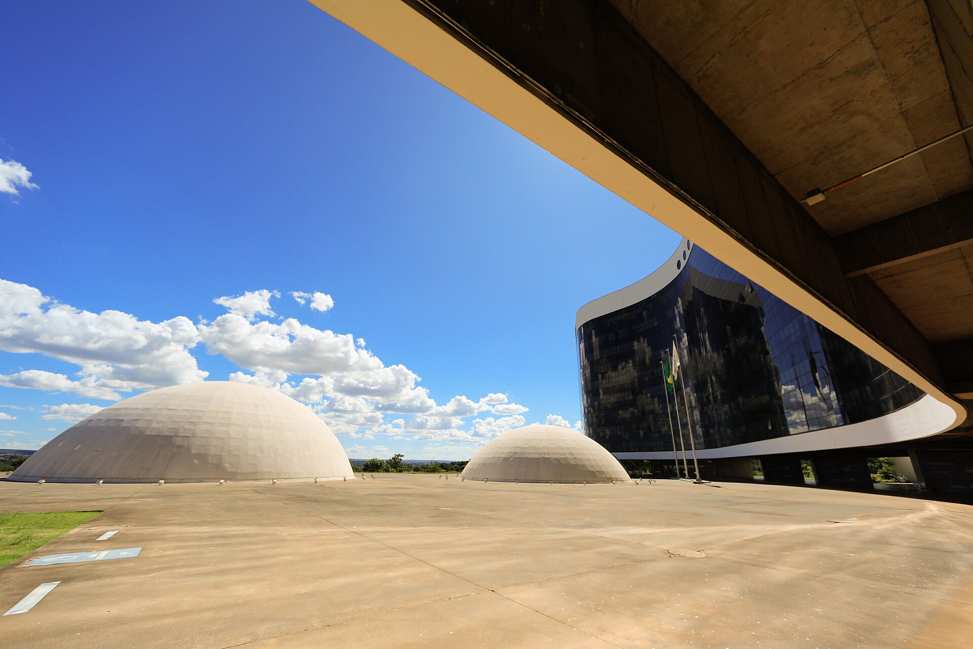 Two white domes and the glass-fronted Superior Electoral Court building under a blue sky in Brasilia, Brazil
