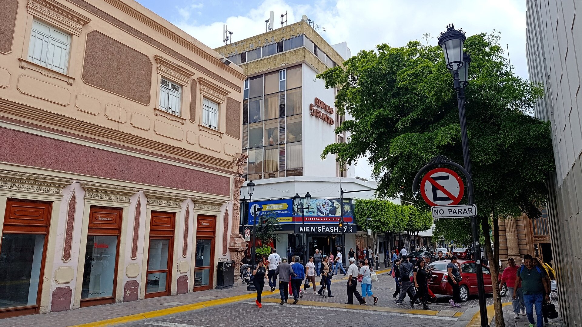 Pedestrians cross a street in the historic centre of León, Guanajuato, past colonial and modern buildings