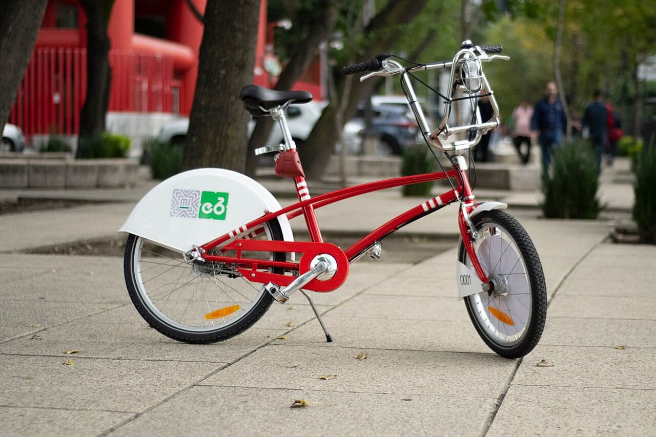 A red and white Ecobici shared bicycle parked on a pavement in Mexico City