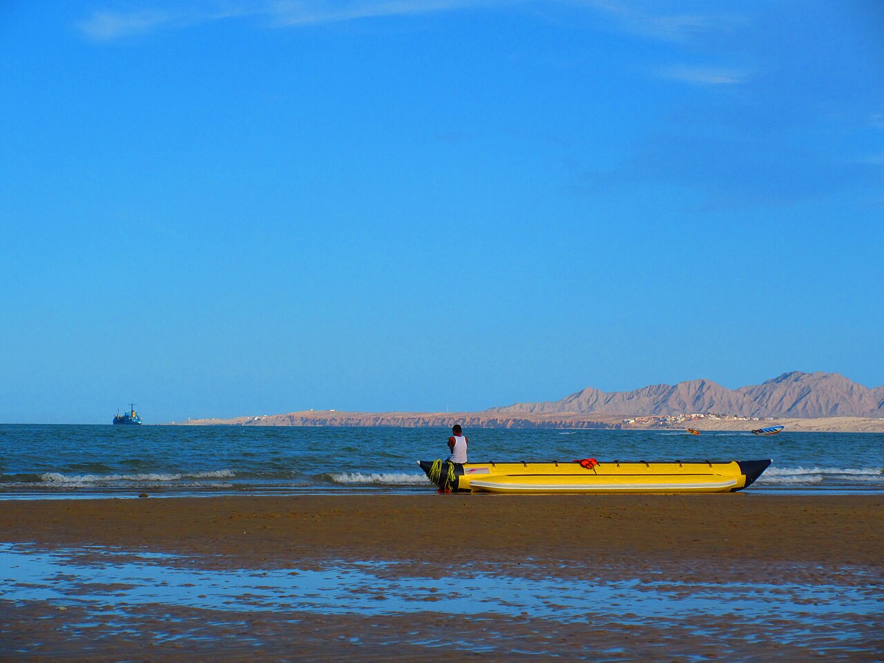 A yellow inflatable boat on a sandy beach at San Felipe with calm blue water and brown desert mountains behind