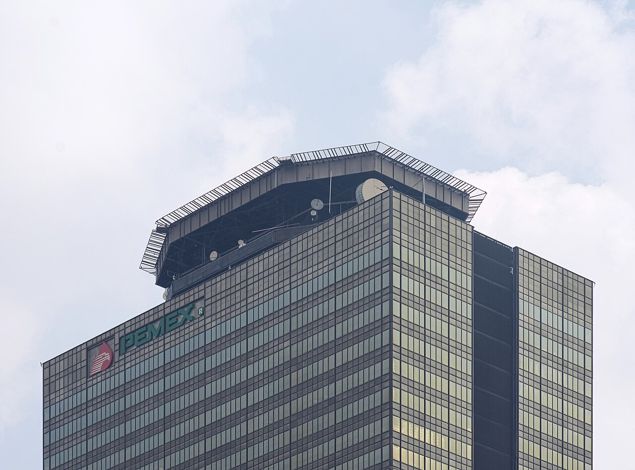 The top floors of the Pemex executive tower in Mexico City, with the green Pemex logo and eagle emblem on its glass facade