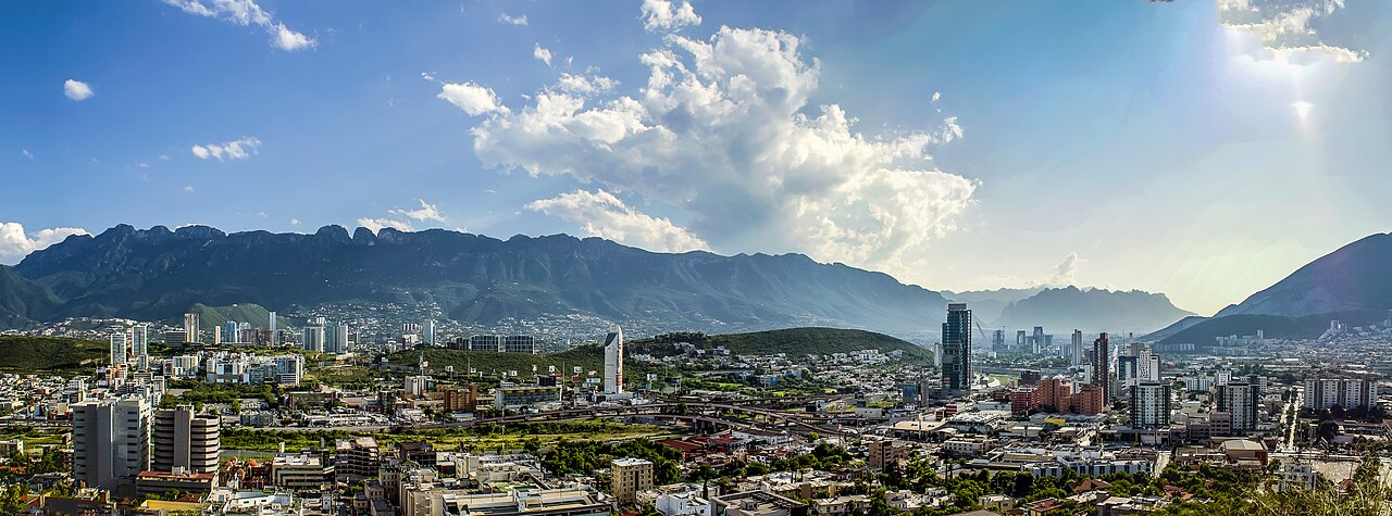 Daytime panorama of Monterrey, Mexico, with city blocks in the foreground and the Sierra Madre ridge behind