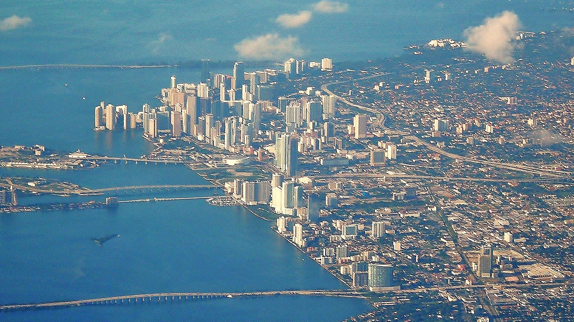 Aerial view of downtown Miami, Florida, with high-rise towers beside Biscayne Bay and causeway bridges