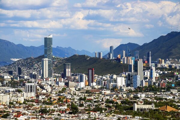 Skyscrapers and houses of Monterrey, Mexico, with the Sierra Madre mountains and cloudy sky behind