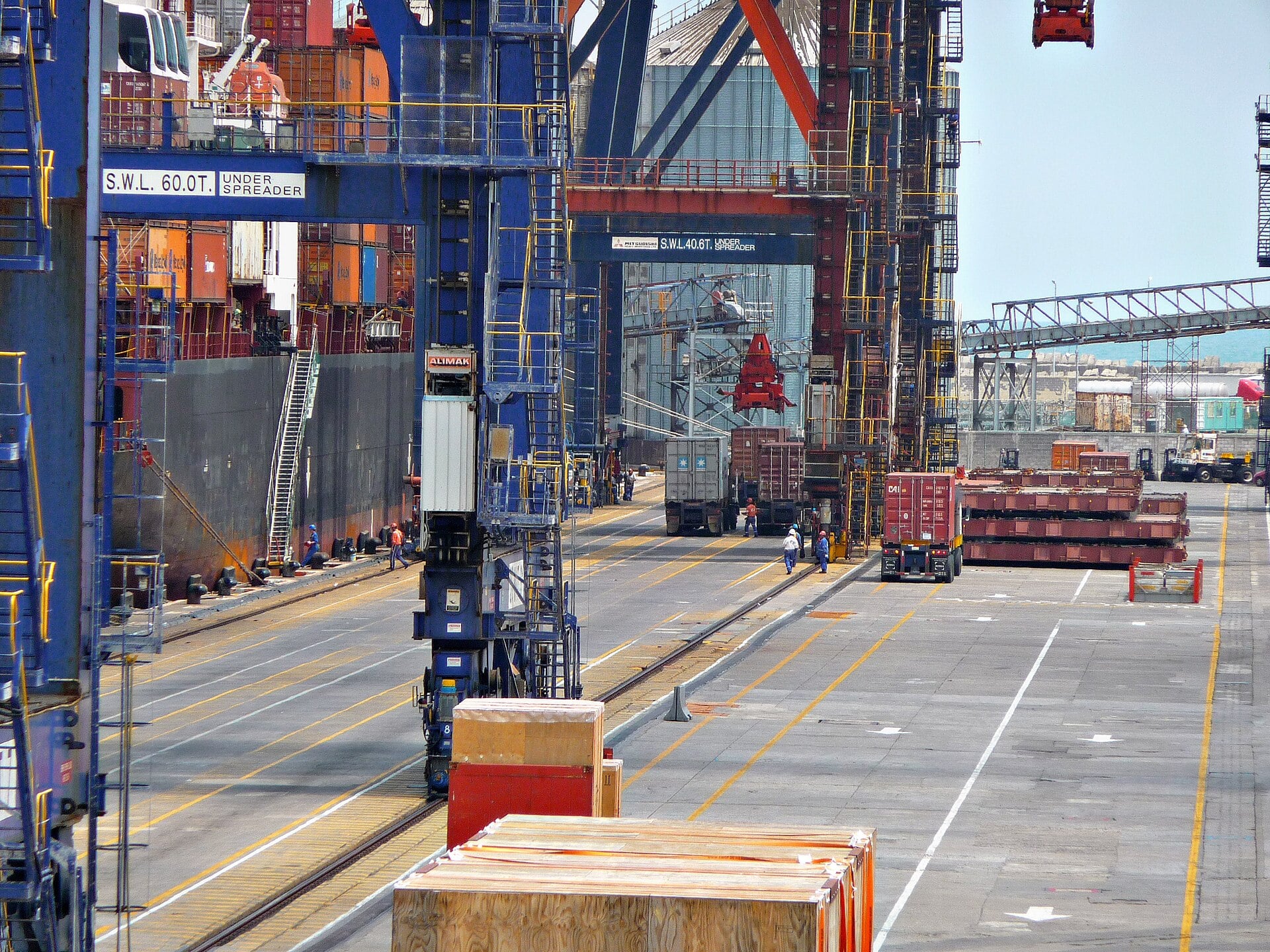 Cranes and trucks handle containers beside a ship at a terminal in the Port of Veracruz, Mexico