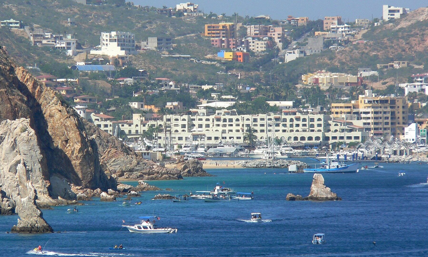 Boats and hotels around the harbor and marina of Cabo San Lucas on a clear day, seen from the water