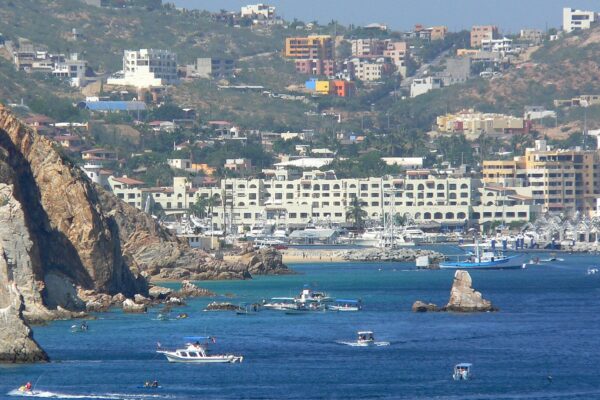 Boats and hotels around the harbor and marina of Cabo San Lucas on a clear day, seen from the water