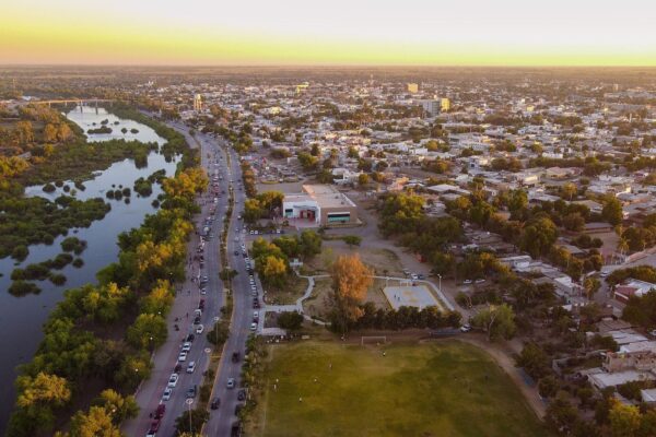 Aerial view of the city of Guasave in northern Sinaloa, Mexico, with a tree-lined river, a main road and houses at sunset