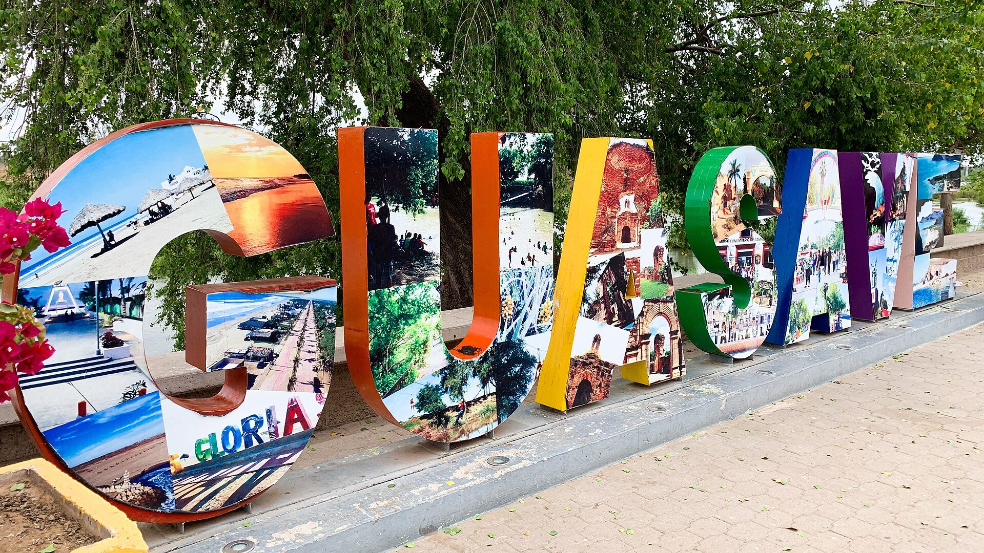 Colourful monumental tourist letters spelling GUASAVE, filled with photo collages, beside a paved walkway in Sinaloa, Mexico