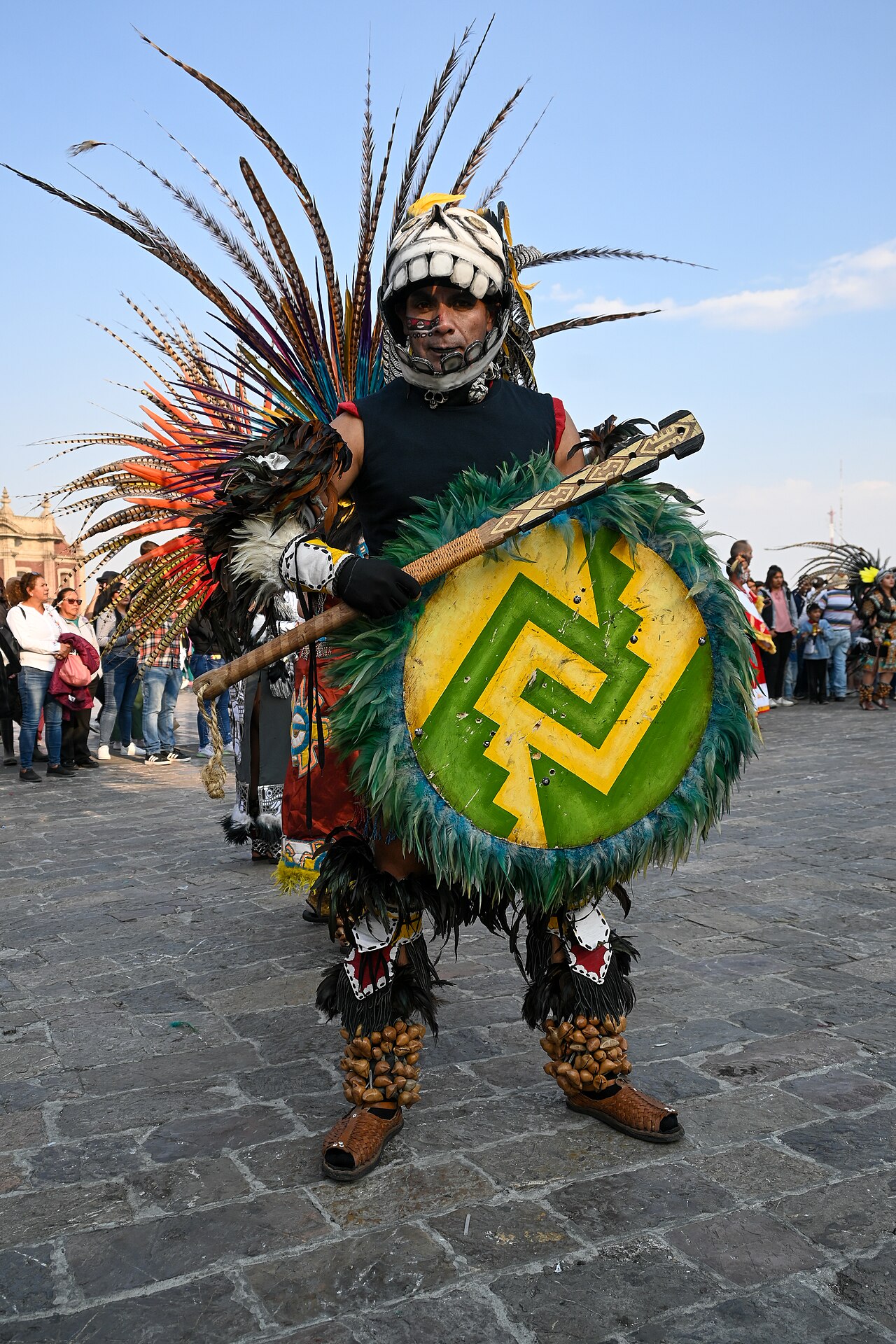 Dancer in a feathered headdress, skull helmet and feathered shield on the plaza of the Basilica of Guadalupe