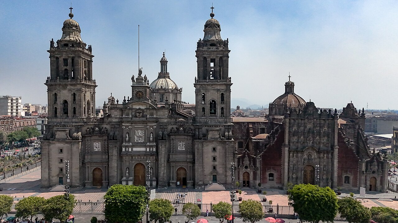 Twin bell towers and stone facade of the Metropolitan Cathedral in Mexico City, with the ornate Sagrario church to the right
