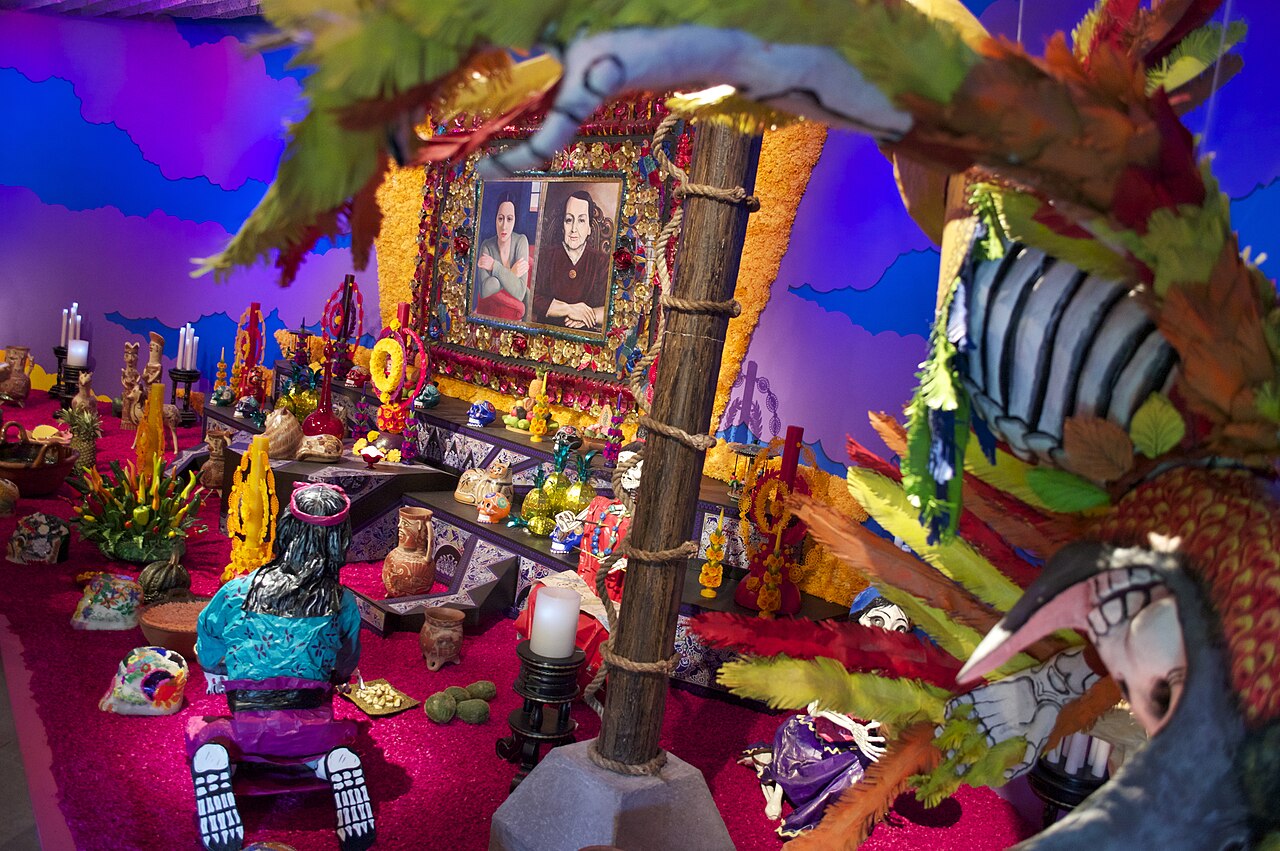 Day of the Dead altar with candles, marigolds, sugar skulls, clay figures and two framed portraits of a woman