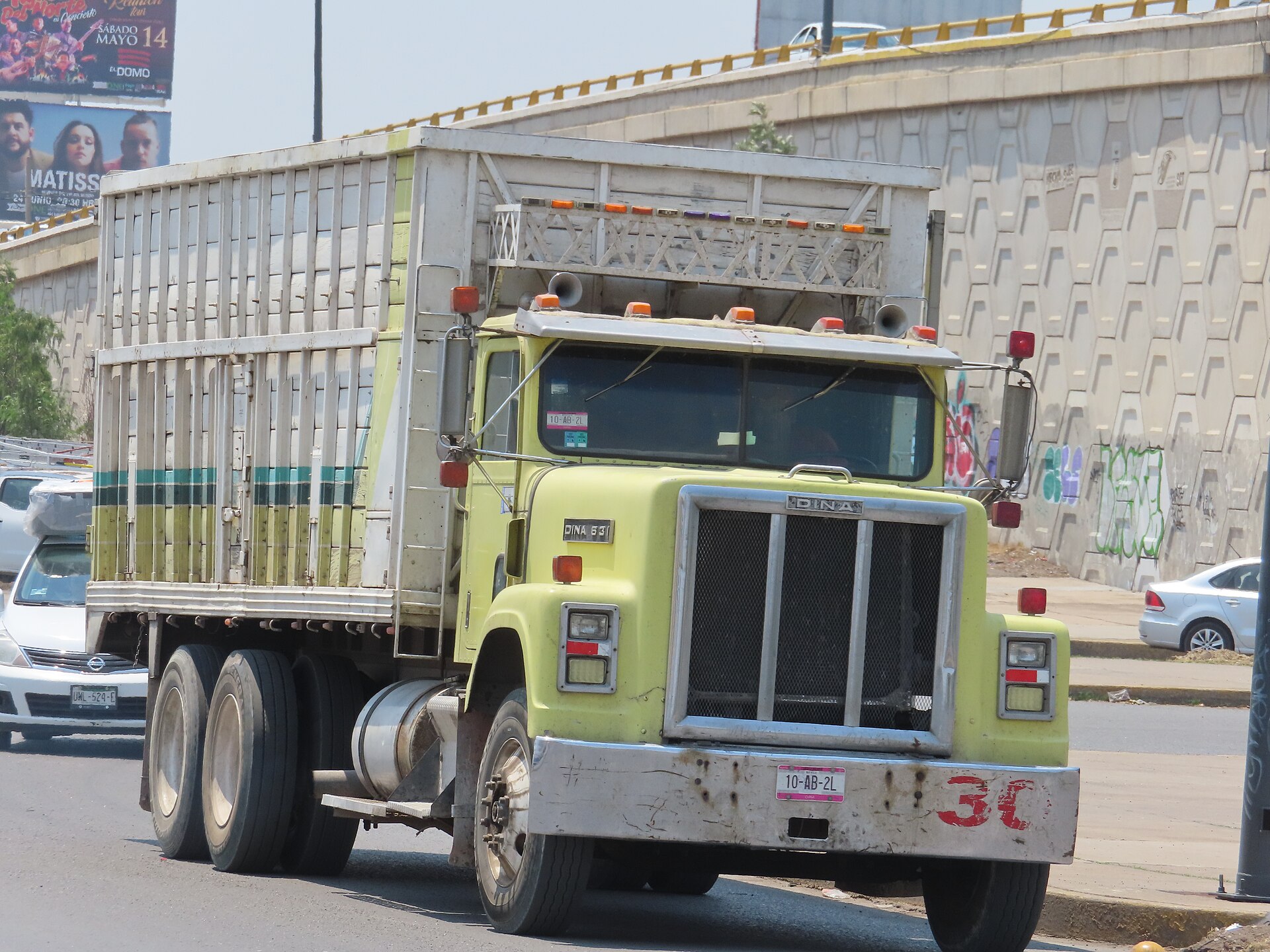 A DINA cargo truck with a slatted wooden body drives on a city road in Mexico