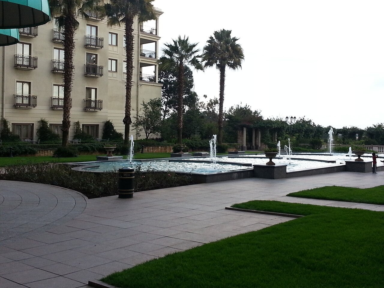 Palm trees and fountains in front of a cream-coloured hotel wing at the Sheraton Addis compound