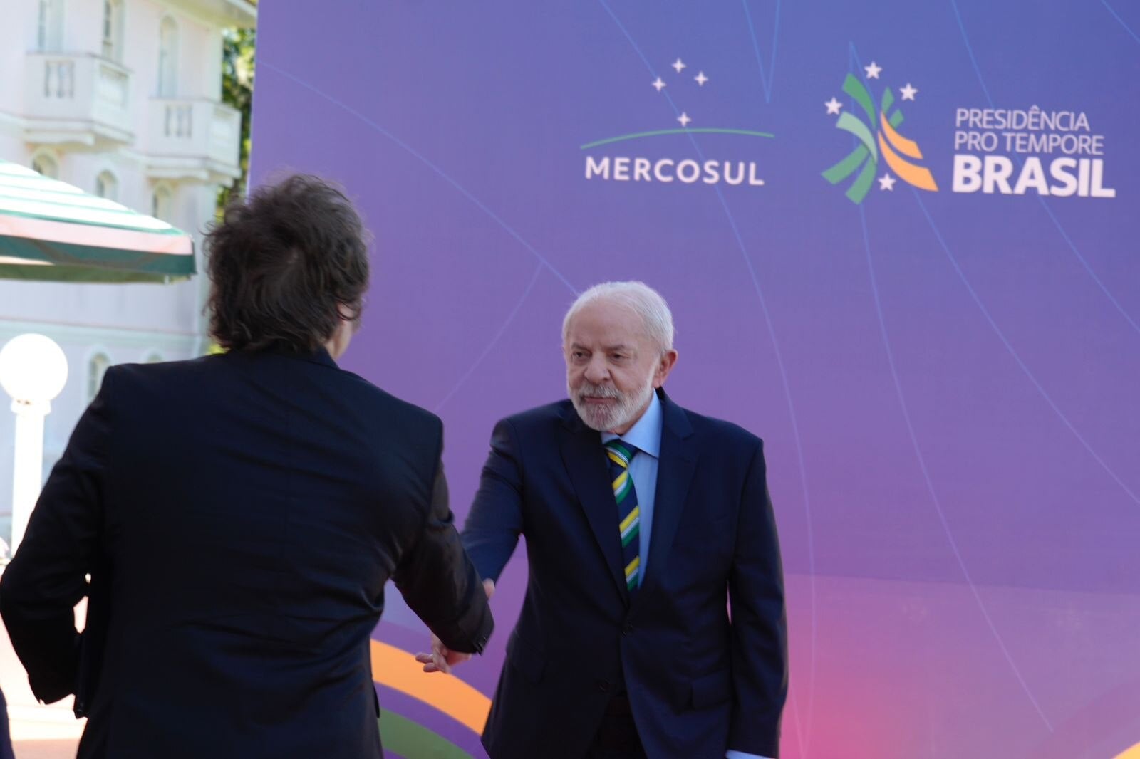 Javier Milei shakes hands with Lula da Silva in front of a Mercosur and Brazilian pro tempore presidency backdrop, December 2025