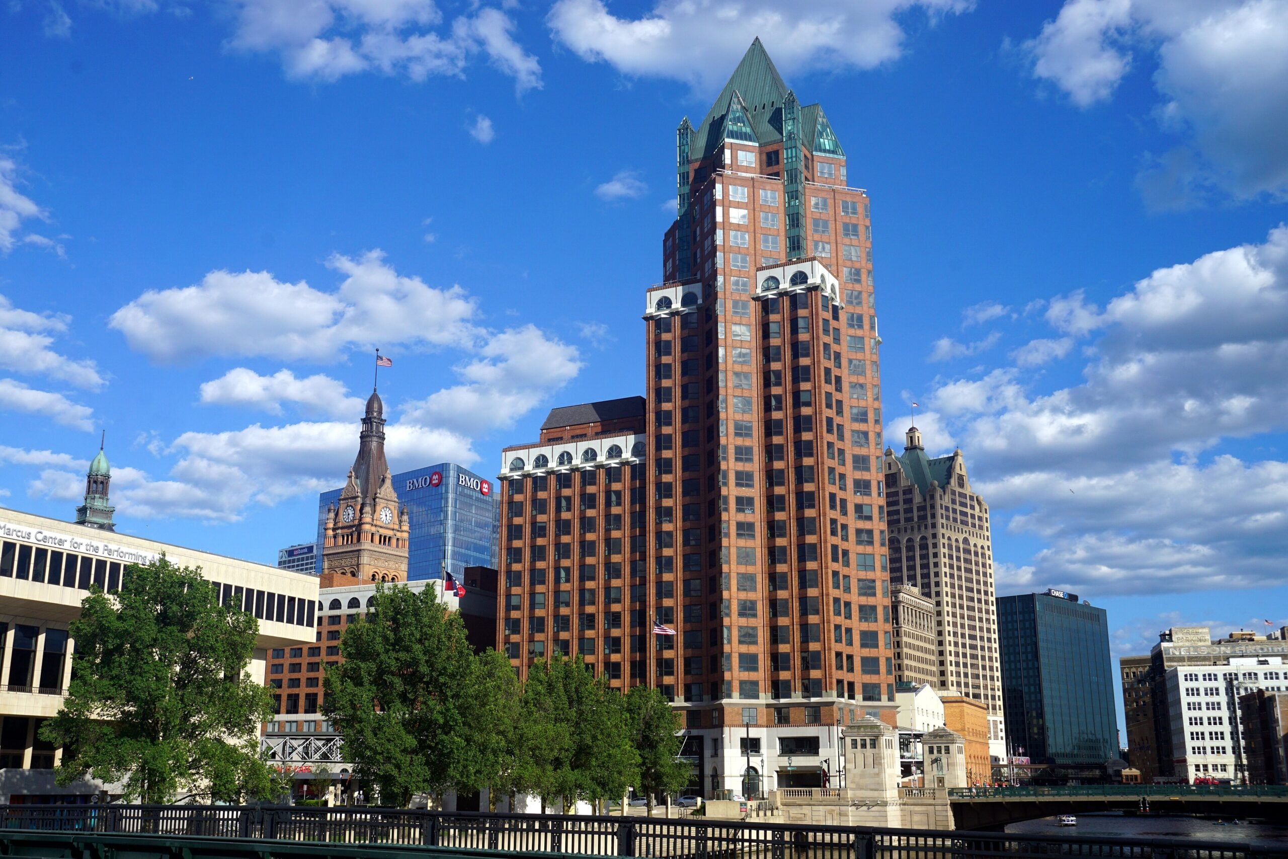 Downtown Milwaukee skyline with a brick office tower and the city hall clock tower under a blue sky