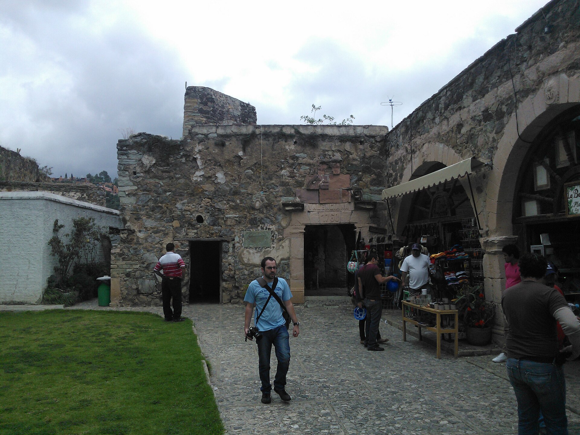 The stone entrance of the Cayetano mine at La Valenciana, Guanajuato, Mexico, with visitors and a craft stall