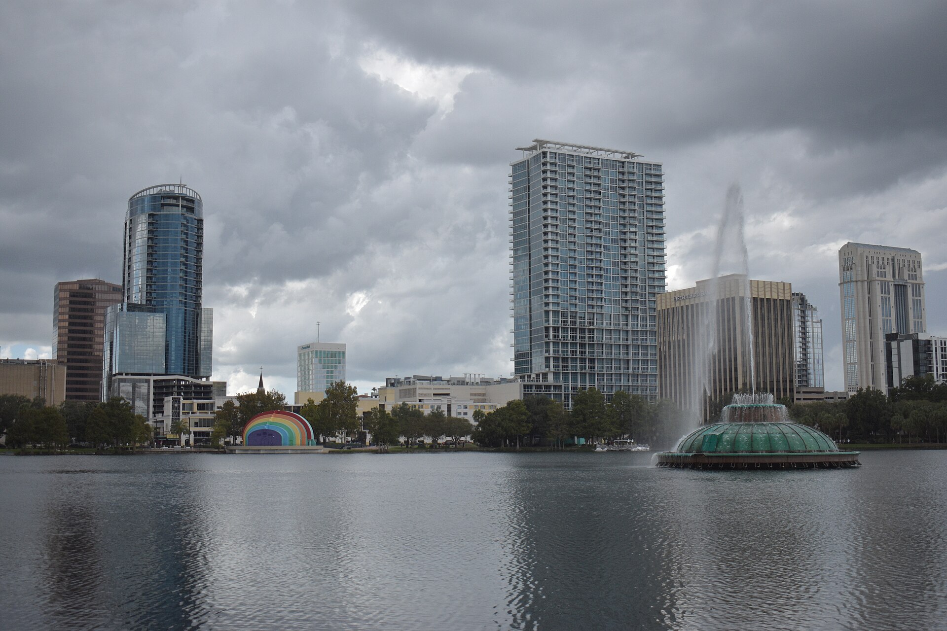 Lake Eola and the downtown Orlando skyline under grey clouds, with a fountain in the lake