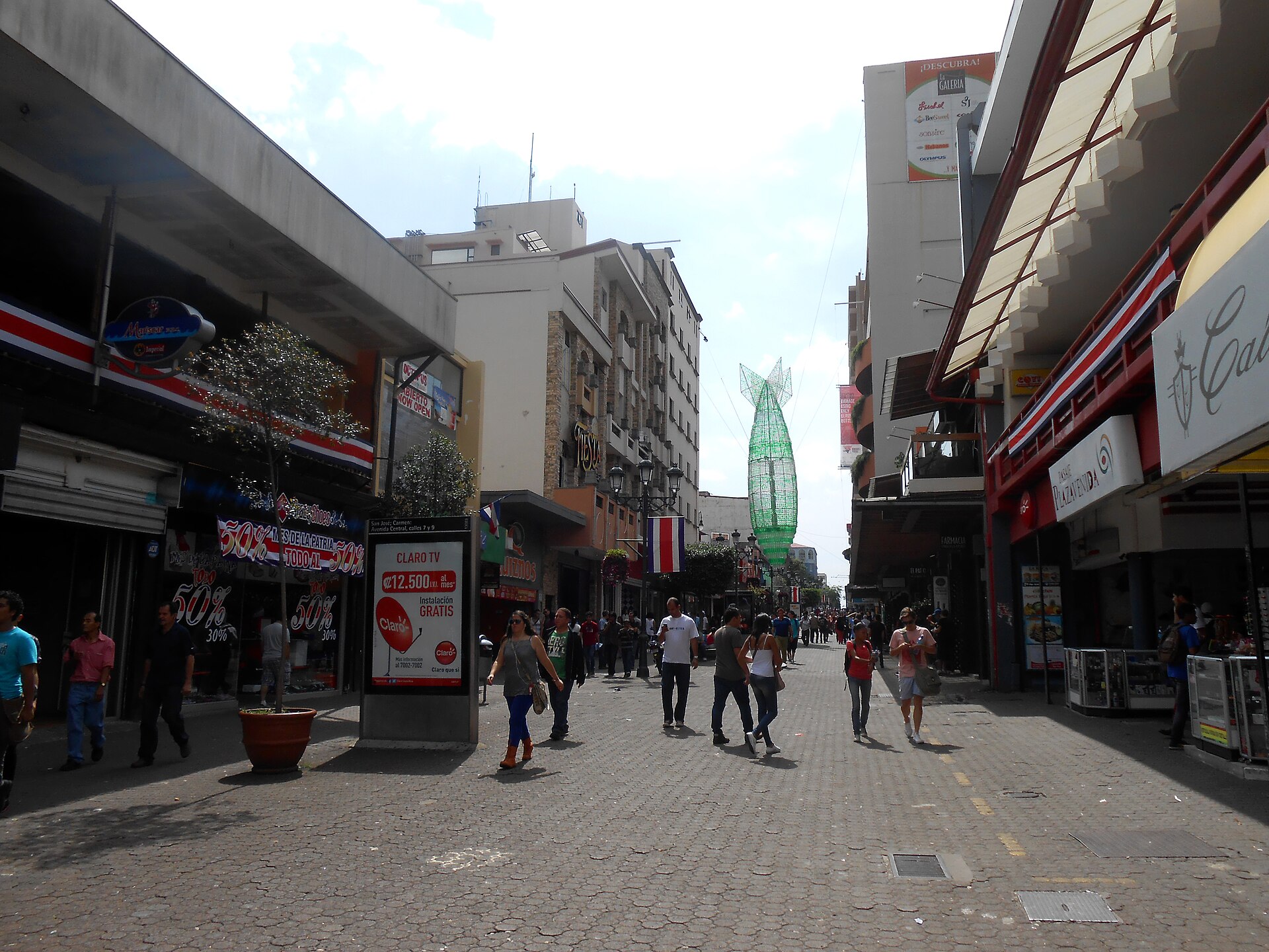 Pedestrians walk along the paved Avenida Central in downtown San Jose, Costa Rica, between shops and flags