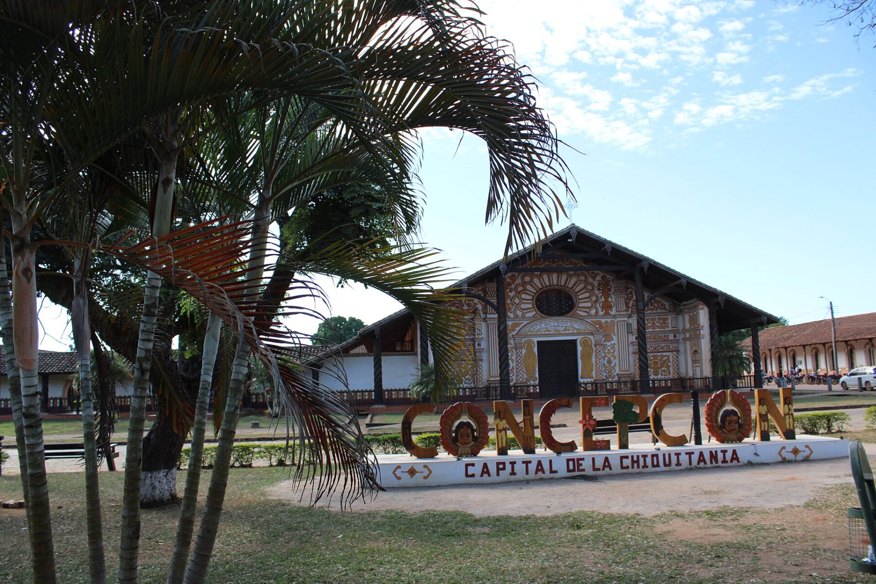The Jesuit mission church of Concepción behind a town sign and palm trees on the main square, Santa Cruz department, Bolivia