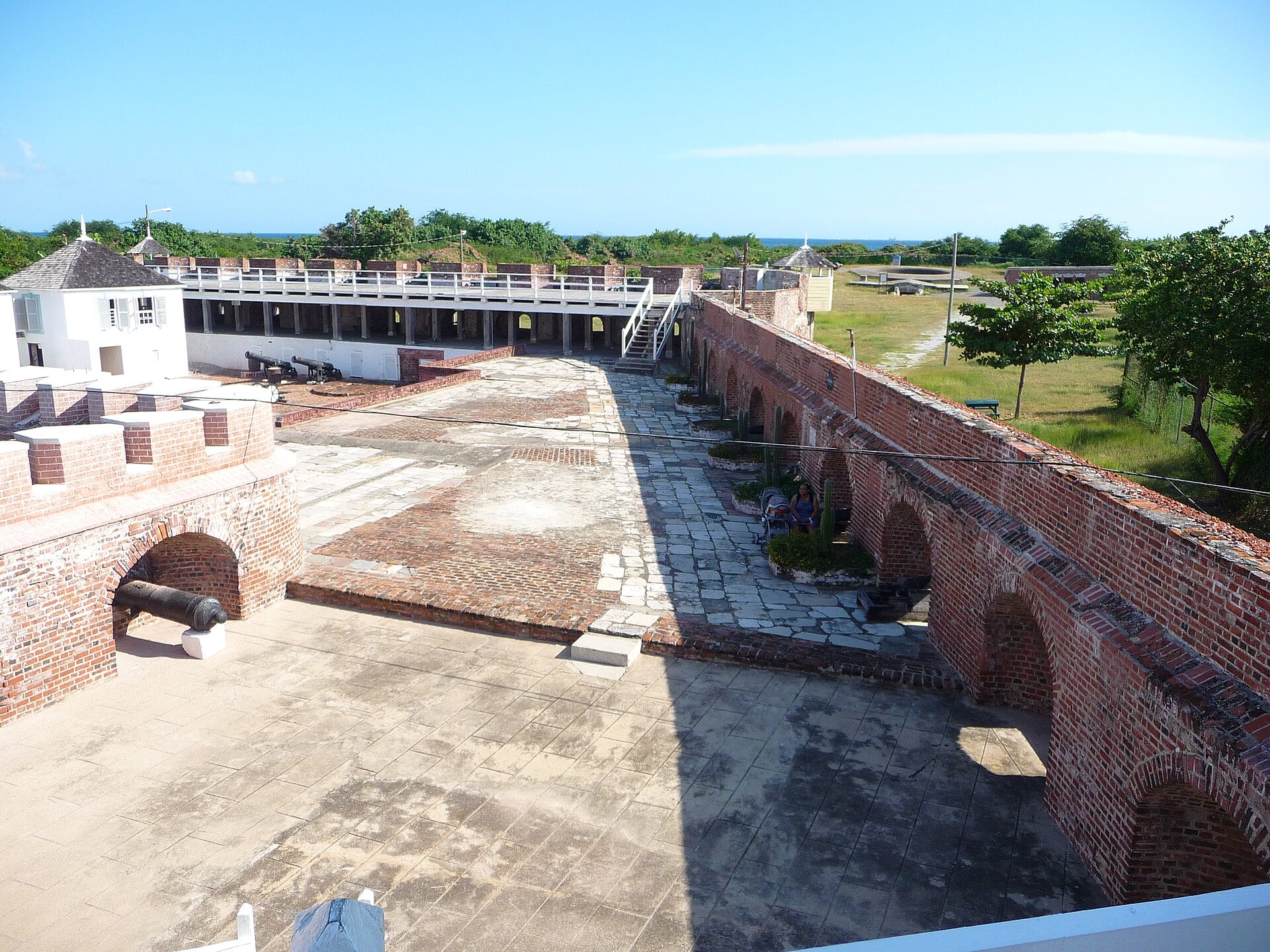 The brick courtyard, arched walls and cannons of Fort Charles at Port Royal, Jamaica, under a blue sky