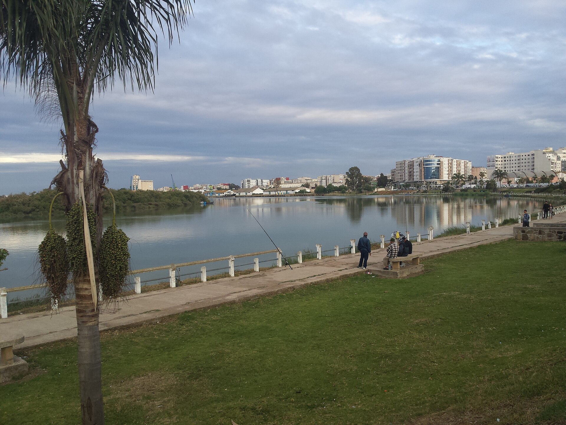 The Sebou River waterfront in Kenitra, Morocco, with port cranes and apartment blocks on the far bank