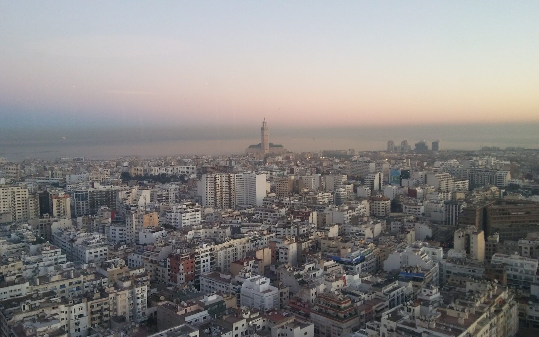 Morocco media: rooftop satellite dishes across Casablanca with the Hassan II Mosque on the horizon