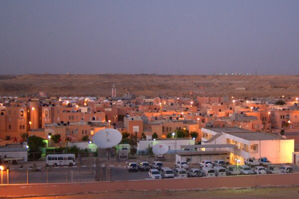 Dusk view of the MINURSO compound in Laayoune, Western Sahara, with UN vehicles and satellite dishes in front of low pink buildings