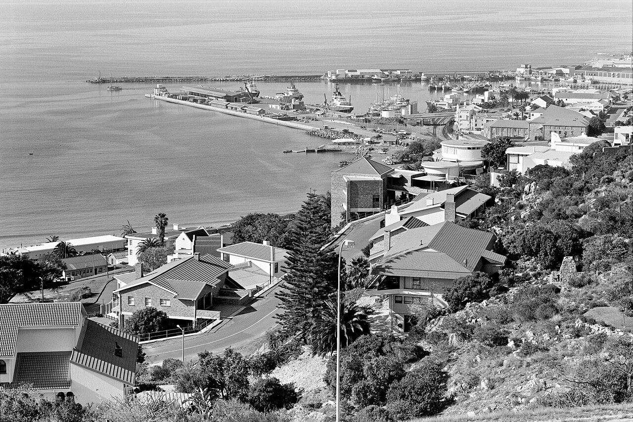 Black-and-white view over Mossel Bay harbour, the bay and the Santos Beach area from the hillside above the town.