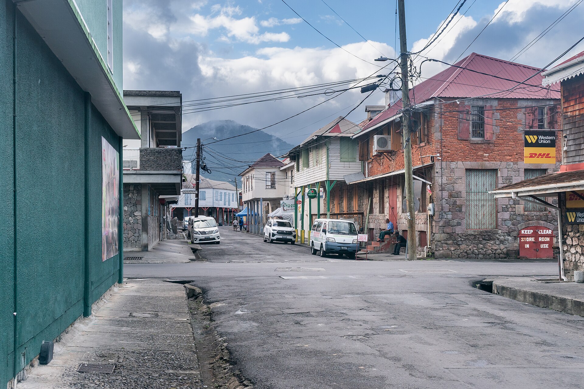 Moving to Dominica: Hanover Street in Roseau, with two-storey stone and wooden buildings, parked cars and green hills behind