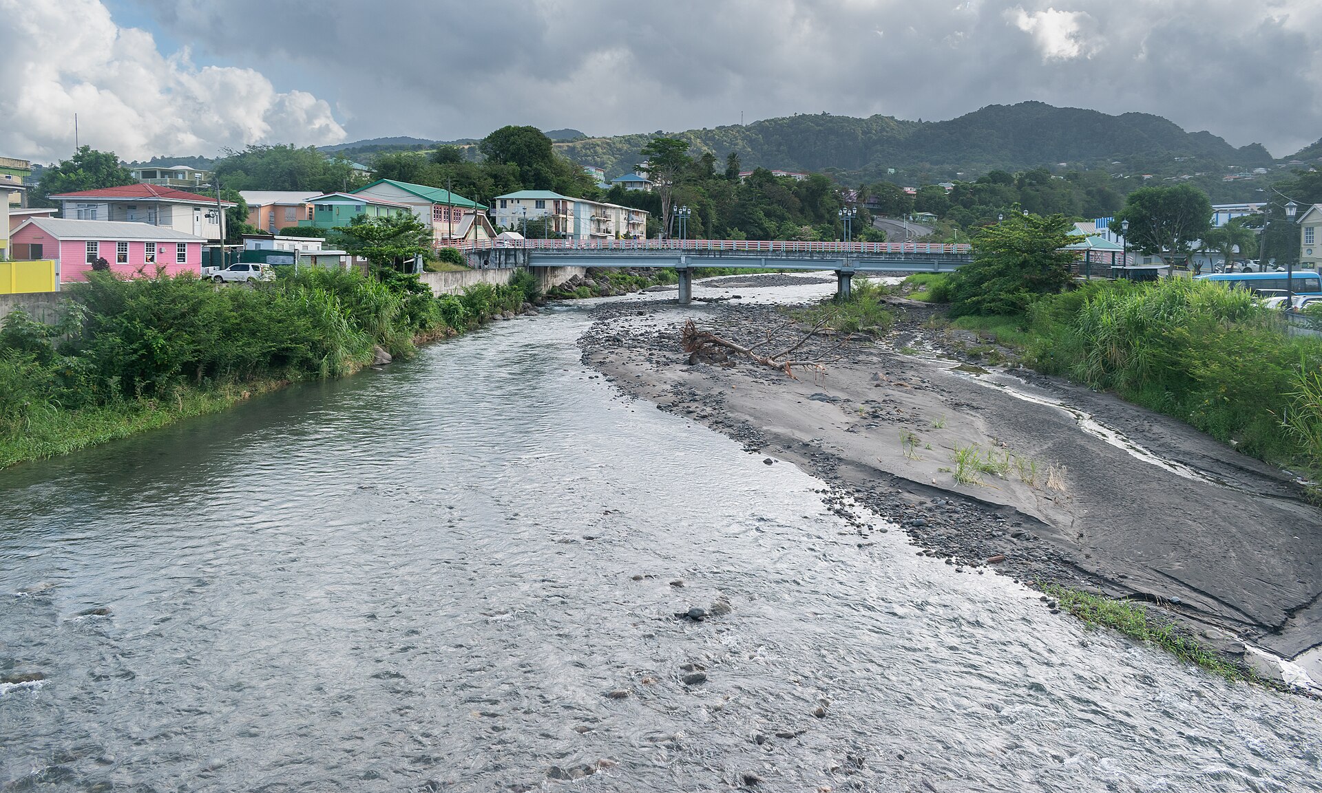 Moving to Dominica: the Roseau River running through Roseau, with a bridge, colourful houses and forested hills