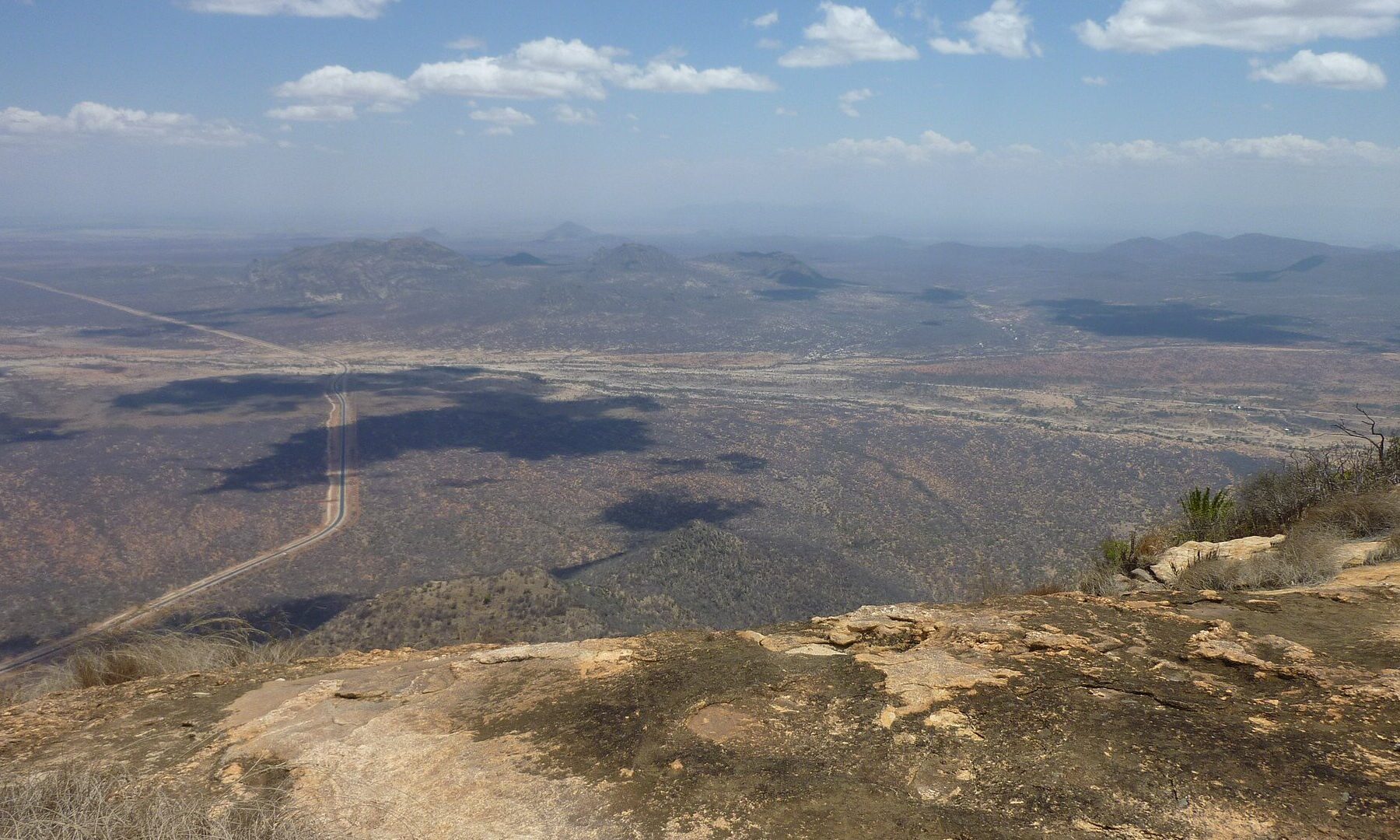 Paved road crossing the dry plains of northern Kenya between Marsabit and Moyale, seen from a hilltop