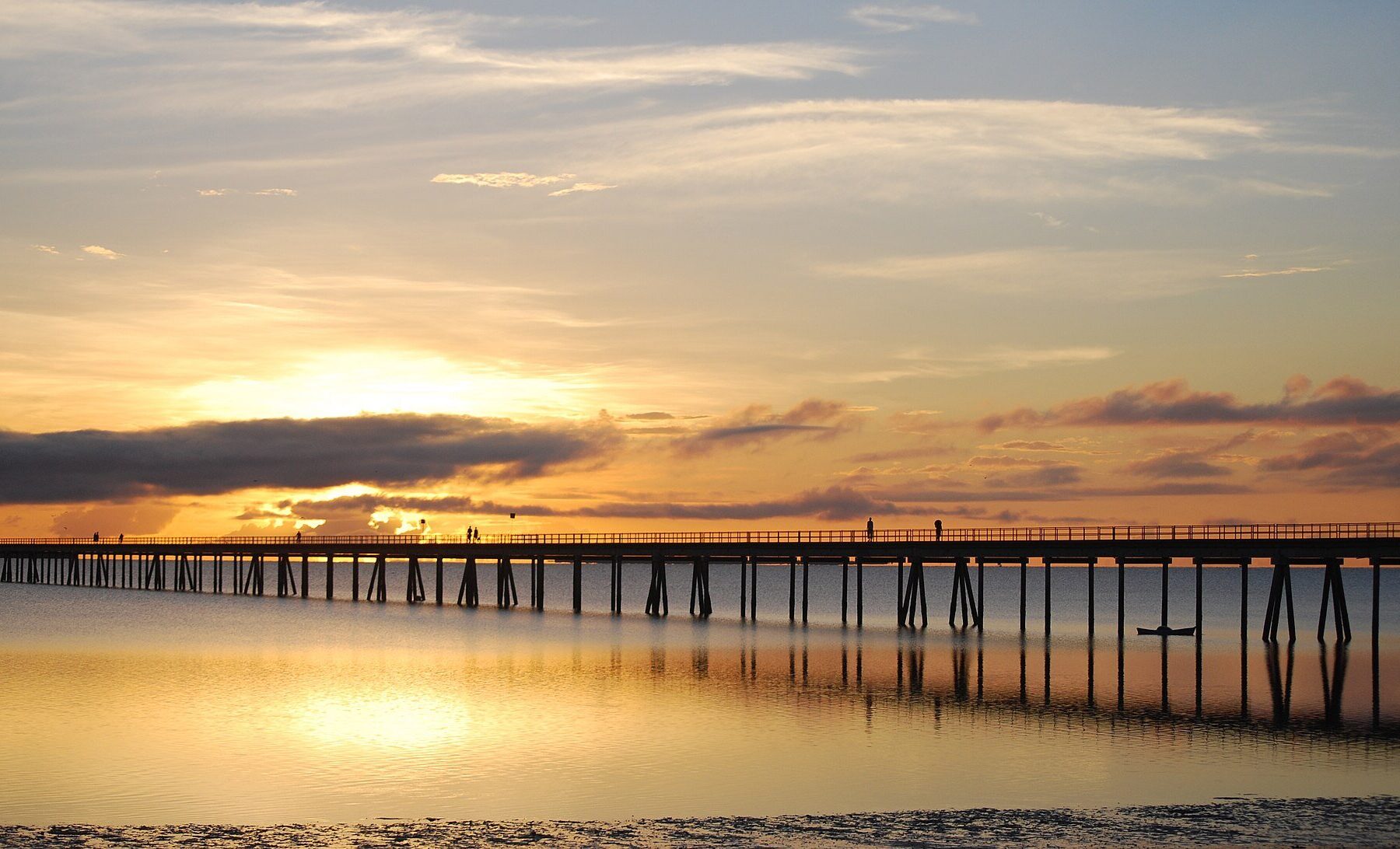 Long wooden footbridge over calm water at sunset linking the Island of Mozambique to the mainland