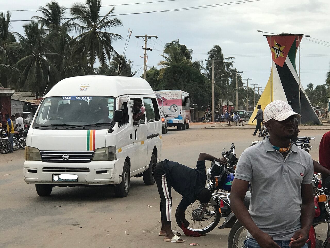 A street in Pemba, in Cabo Delgado Province, with a minibus, motorbike taxis and a monument painted as the Mozambican flag