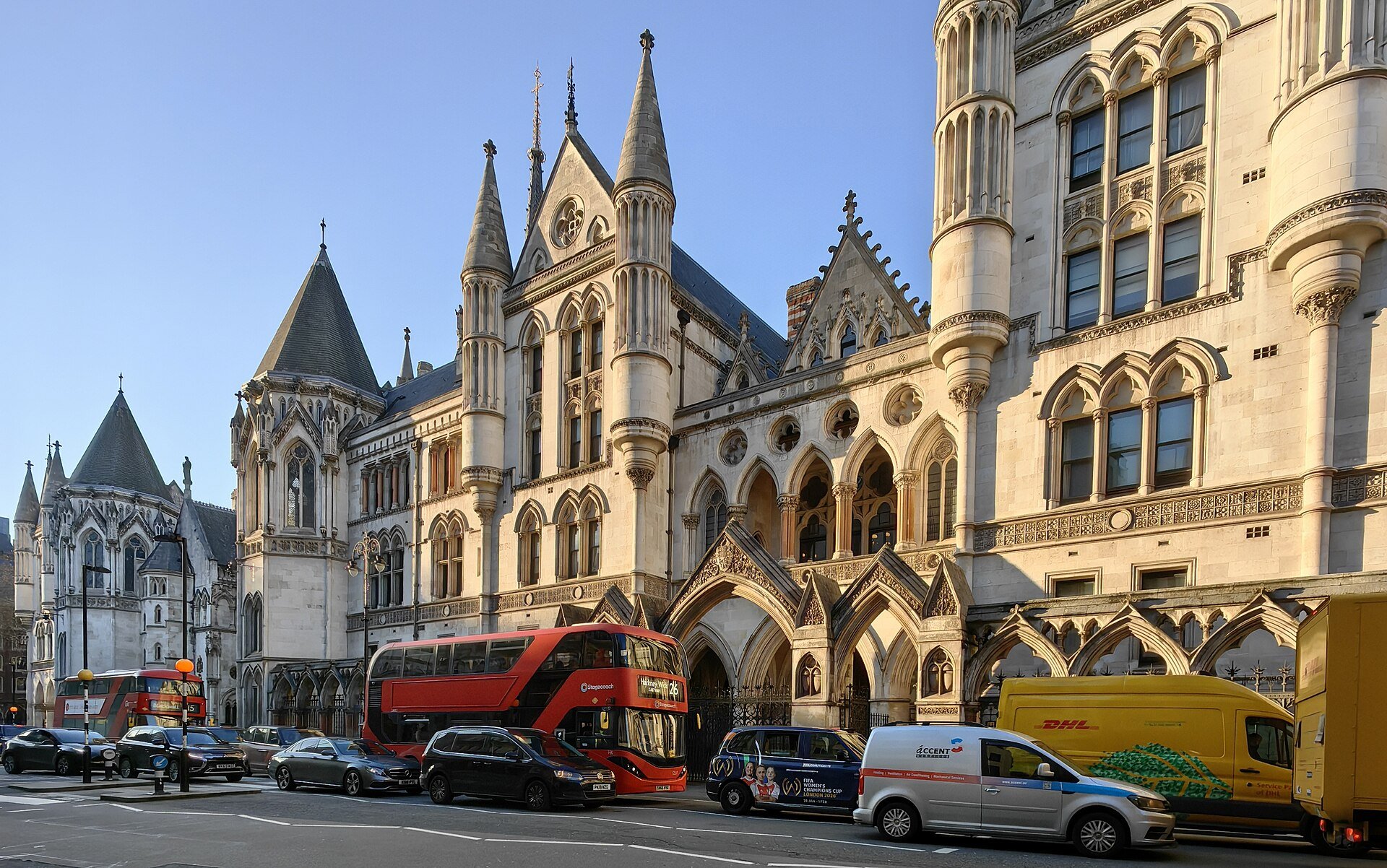 The Gothic front of the Royal Courts of Justice in London with buses and vans on the street