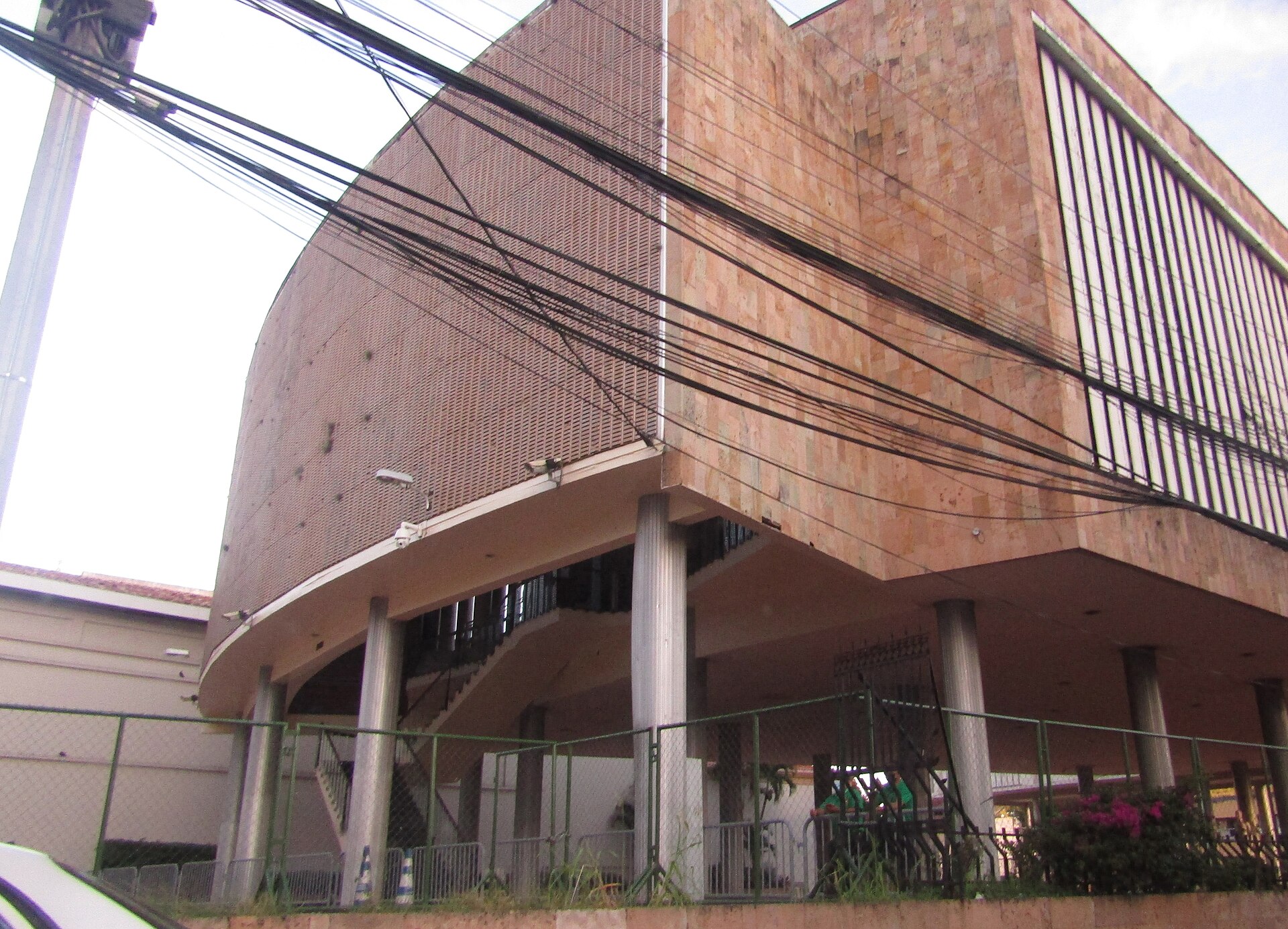 Curved pink stone facade of the National Congress building in Tegucigalpa with overhead cables and columns at street level