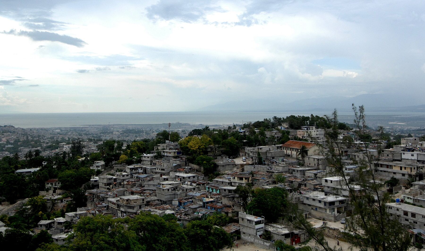 Hillside houses of Port-au-Prince under a cloudy sky with the bay and distant mountains behind